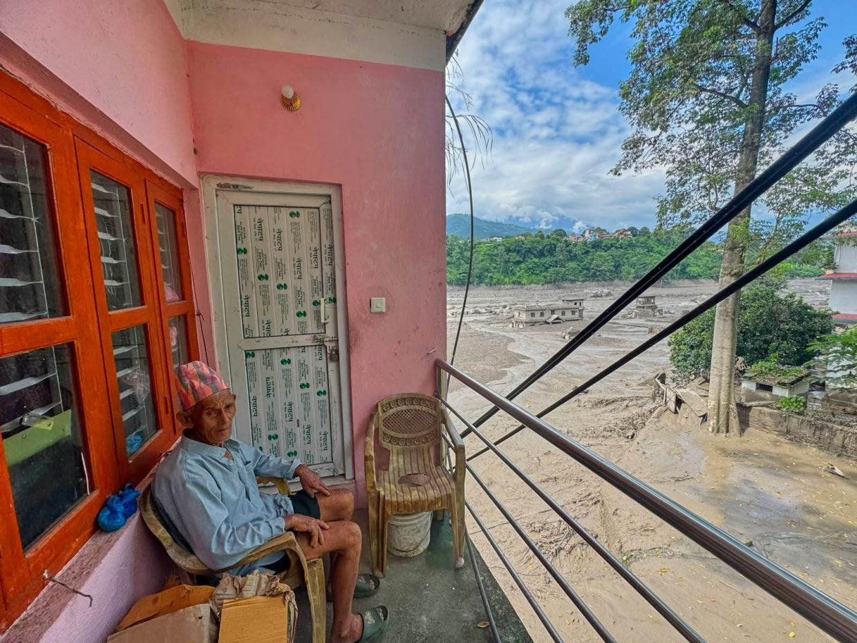 A resident sits on the balcony of his house surrounded by floodwaters and debris after flash floods caused the Trishuli River to swell in Nepal's Nuwakot district, Wednesday, Aug 26, 2026. - Photo: AP 