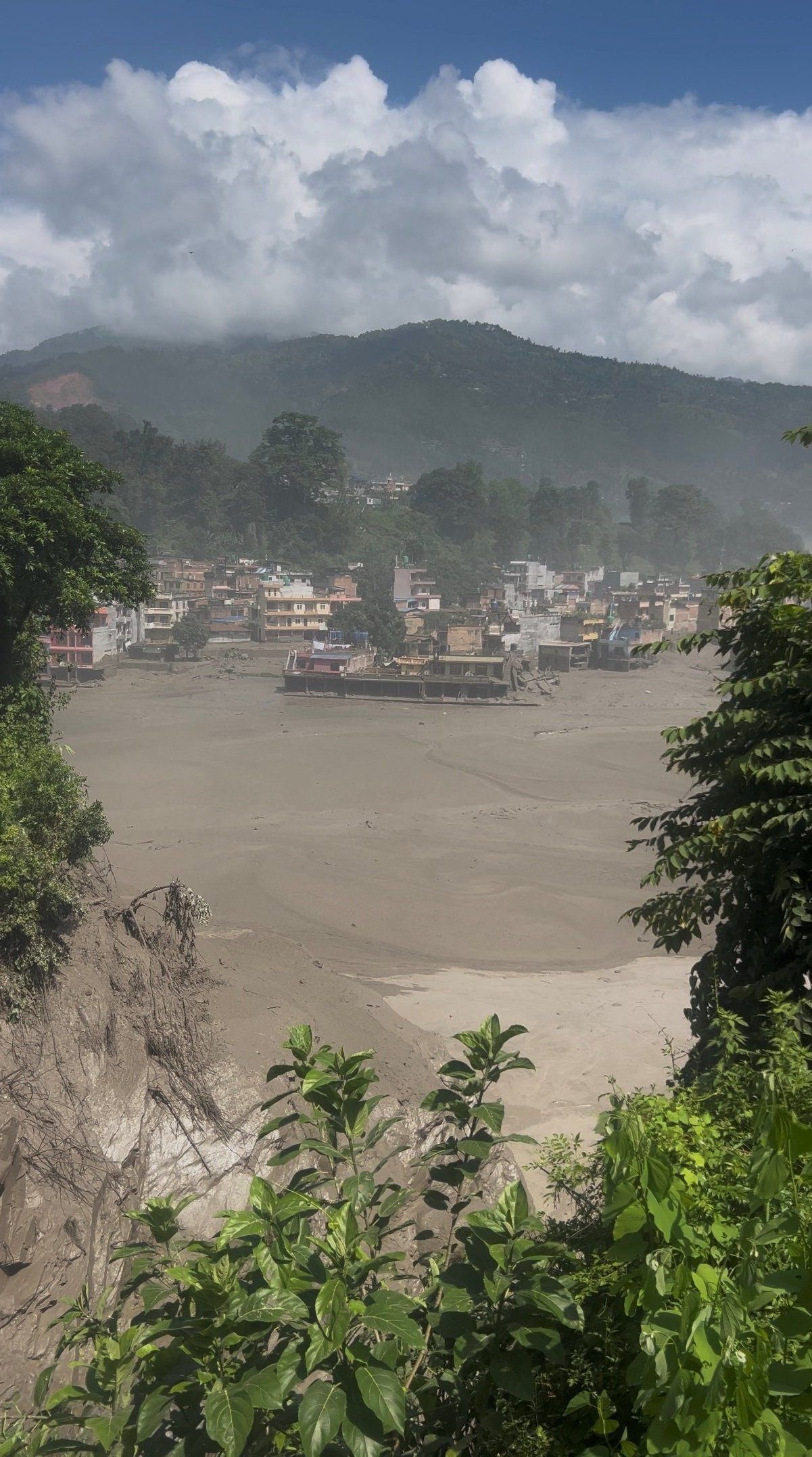 Partially submerged buildings along the riverbank due to a flash flood in Nuwakot district, Nepal, August 26, 2026, in this screen grab obtained from a handout video. - Photo: Handout via Reuters