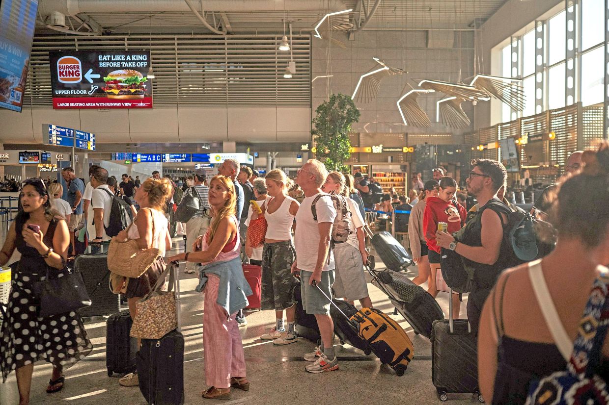 Passengers checking screens of fight info at the departure hall of Athens' Eleftherios Venizelos international airport