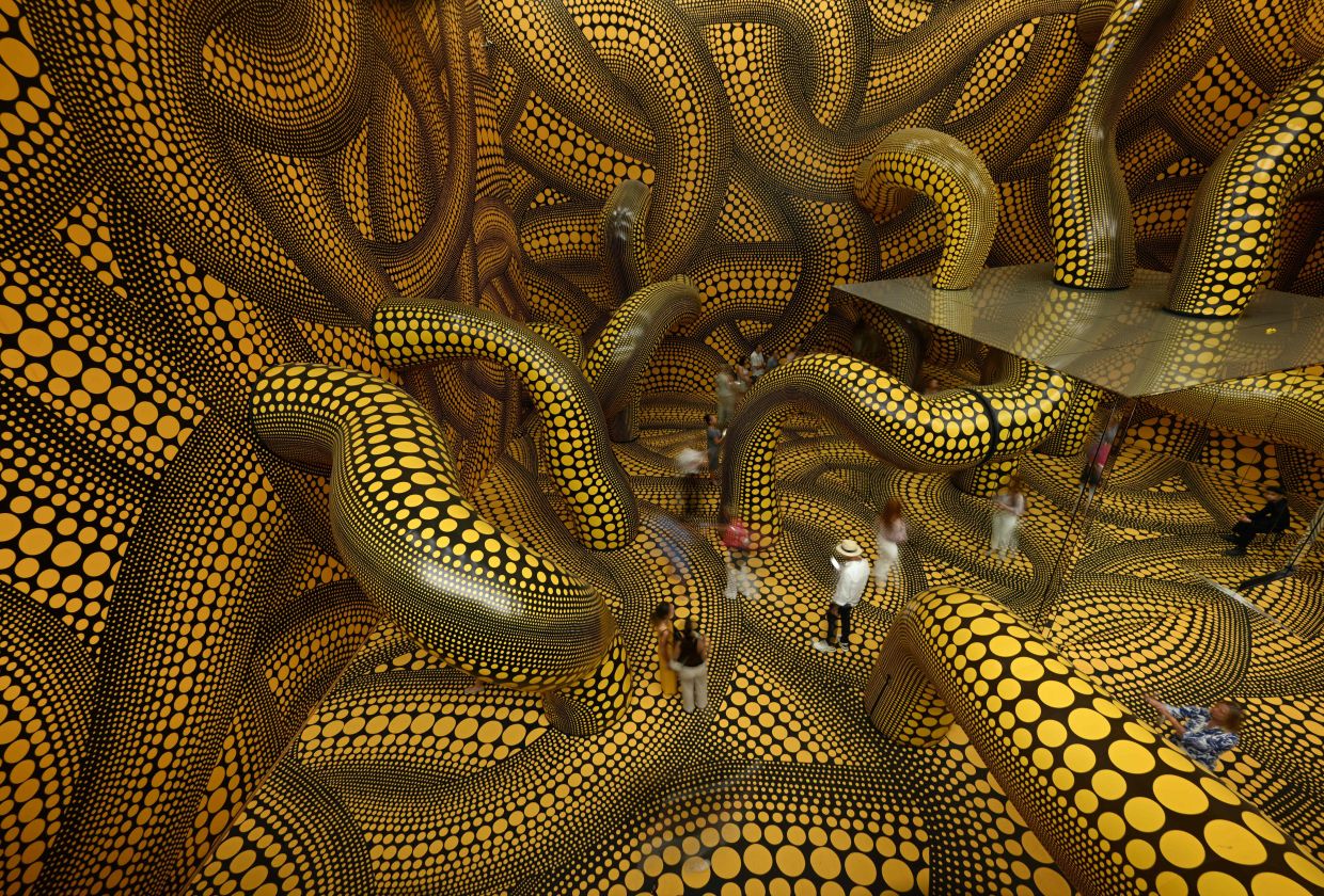Visitors walk through the installation 'Infinity Mirrored Room The Hope Of The Polka Dots Buried In Infinity Will Eternally Cover The Universe' at the 'Yayoi Kusama' exhibition at the Museum Ludwig in Cologne, Germany in August 2026. Photo: AFP