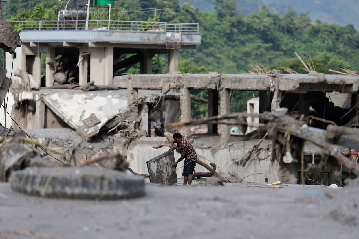 A man salvaging his belongings from mud following the devastating floods, in Trishuli on Aug 27. - Reuters