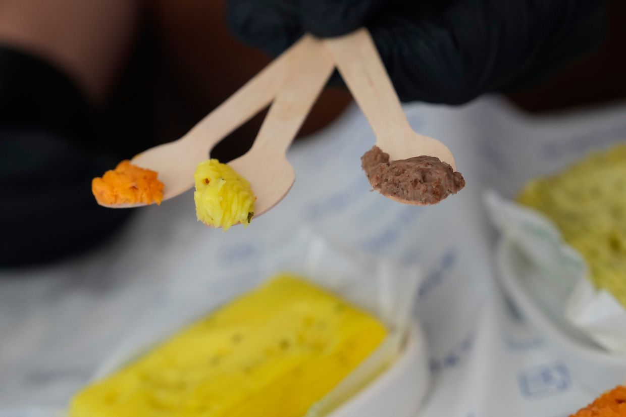 Butter samples in different flavors are offered to customers on wooden spoons at Le Butter Shop.