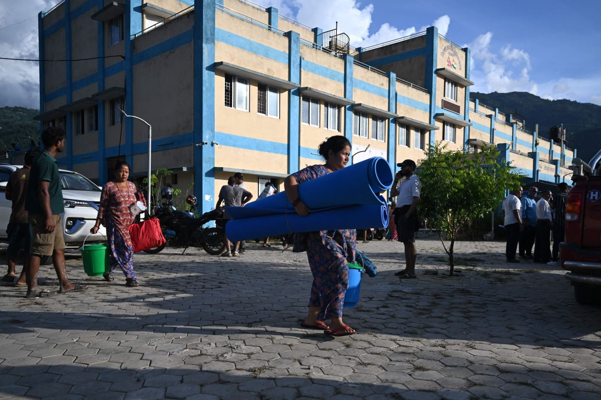 Residents leave after receiving utility aid at a hospital turned temporary shelter after flash floods in the Devighat area of Nepal's Nuwakot district on August 27, 2026. Rescue teams scoured devastated zones August 27 for more than 1,300 people missing a day after flash floods and landslides along the Nepal-Tibet border killed at least 273, sweeping away entire villages. (Photo by Arun SANKAR / AFP)