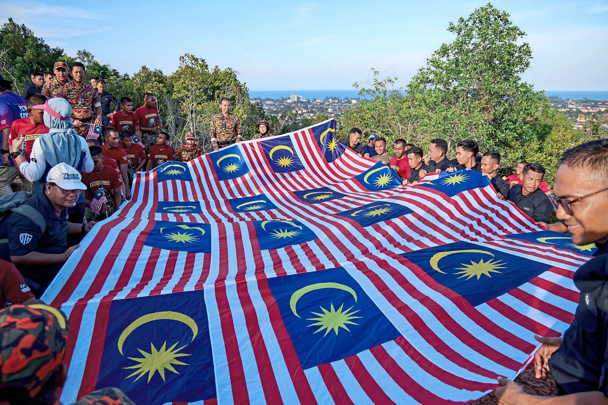 Participants of the hike up Bukit Besar in Kuala Terengganu with their giant mosaic Jalur Gemilang.
