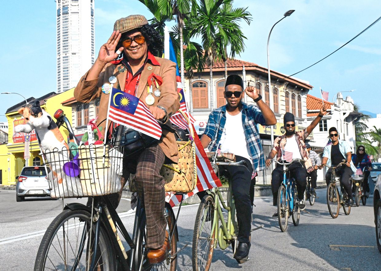A salute for the nation as cyclists on vintage bicycles raise the spirit of patriotism, unity and nostalgia on the streets of George Town, Penang.