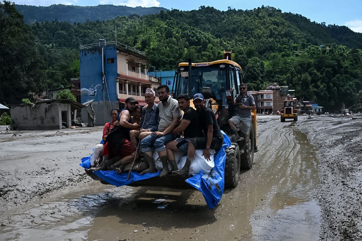 Rescue personnel transport stranded residents using a bulldozer after flash floods in the Devighat area in Nepal's Nuwakot district on August 27, 2026. Rescue teams rushed on August 27 to find more than 1,400 people missing on the Nepal-Tibet border in flash floods and landslides that killed at least 362 and swept away entire villages. - Photo: AFP
