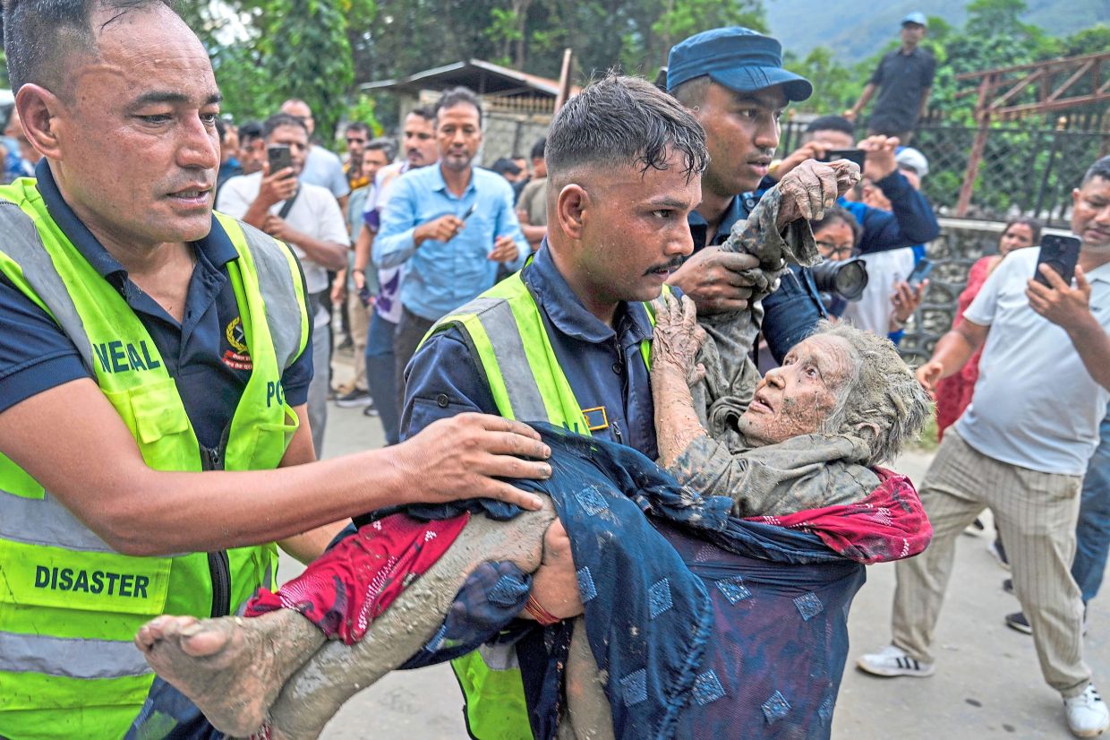In safe hands: Rescuers carrying a flash flood victim to safety along the Trishuli River in Nepal’s Nuwakot district. — AP