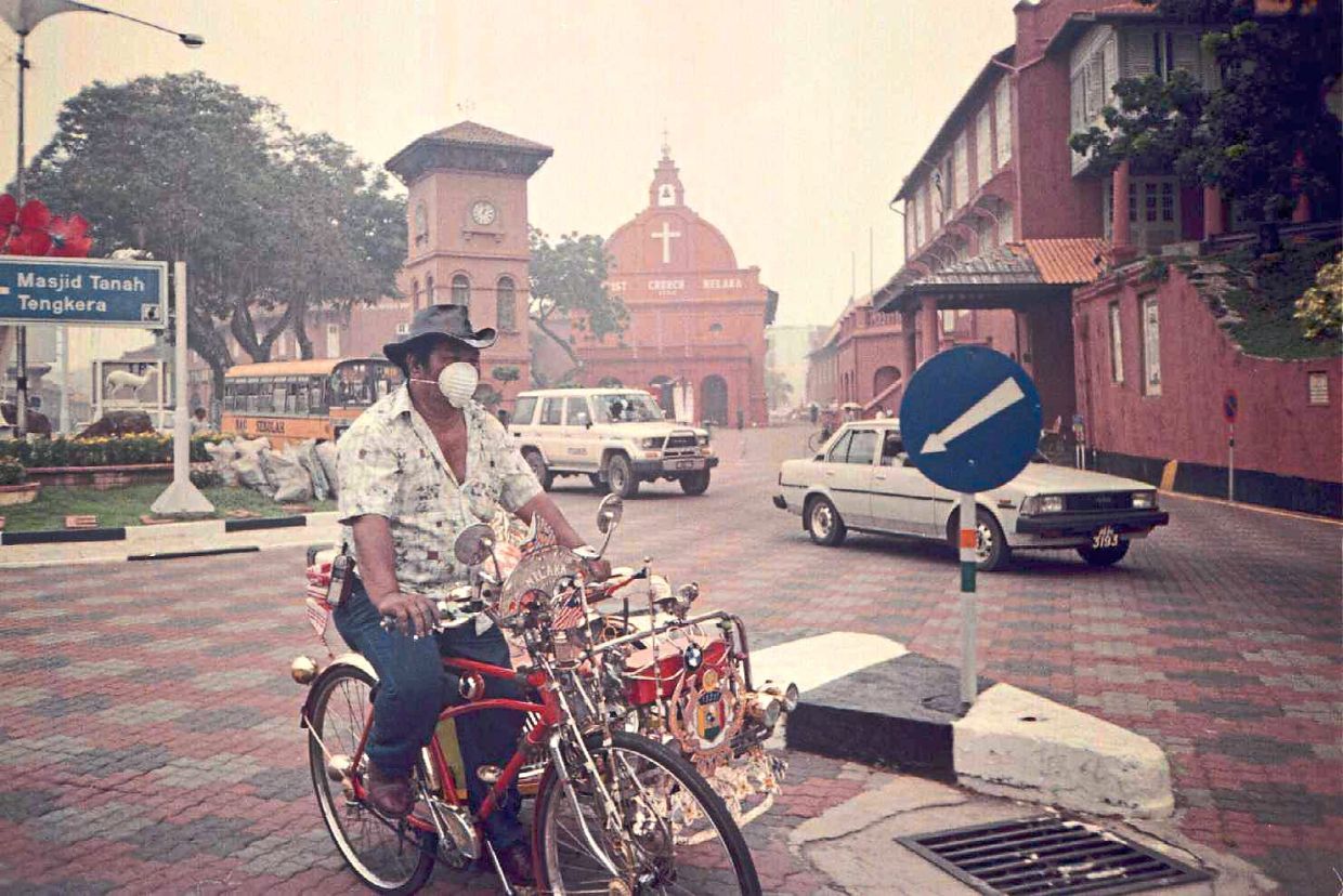 A trishawman pedalling with a mask on to protect himself from haze in Melaka in September 1997.