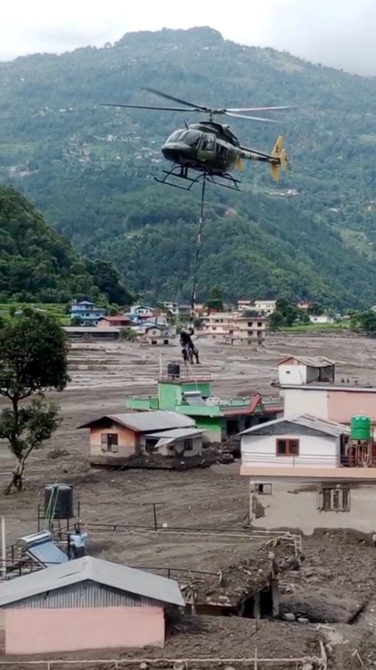 A Nepal Army helicopter flies over houses as they rescue stranded people at an undisclosed location. - Nepal Army handout/Reuters