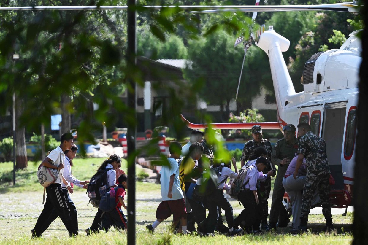 School children board a helicopter on a transit flight back to their family at Trishuli camp after being stranded by flash floods in Nepal's Nuwakot district on Aug 28, 2026. - AFP