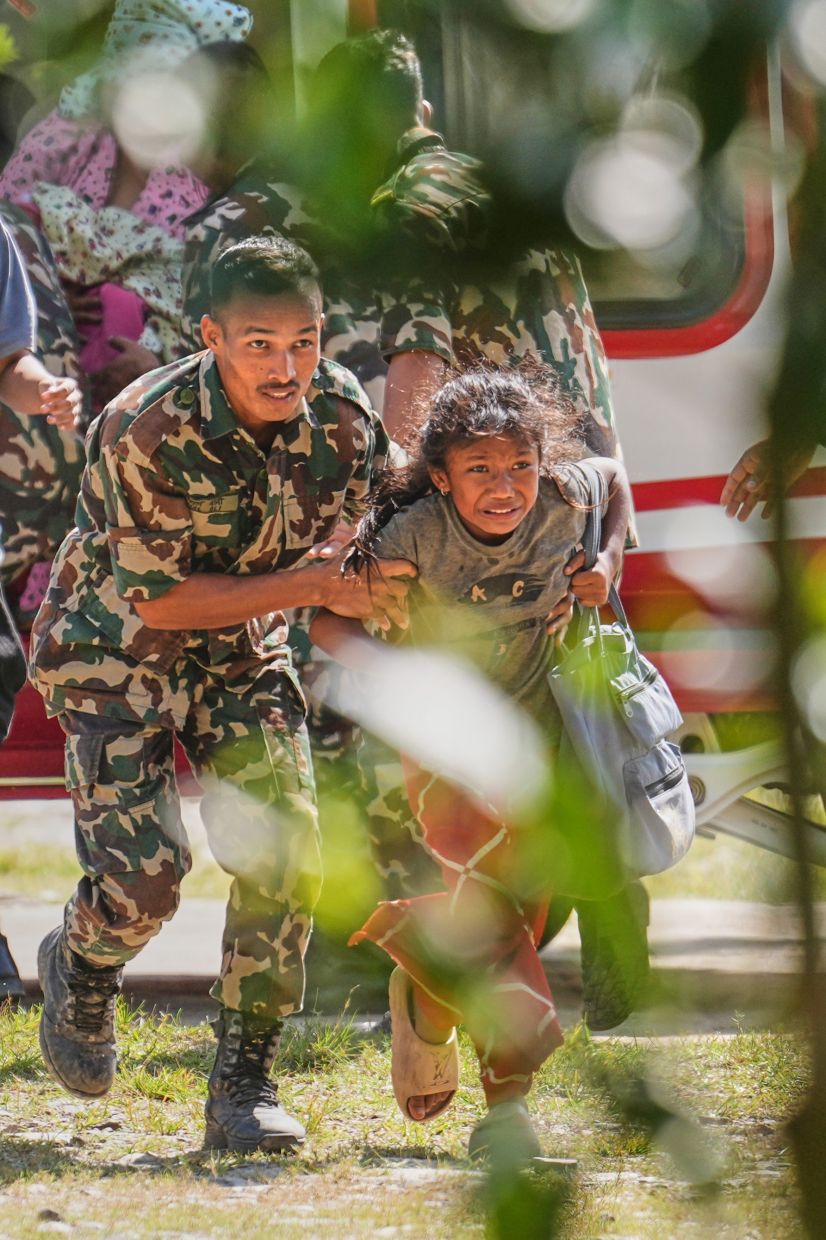 An army soldier helping a girl disembark from a helicopter after she is rescued from an area cut off by flash flooding in Nuwakoton Aug 28, 2026. - AP
