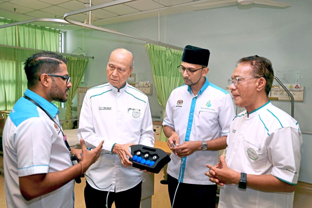 (From left) Dr Vairavanathan explaining to Lee, Dr Faizal Nizam and Prof Zahari about the shockwave therapy system.