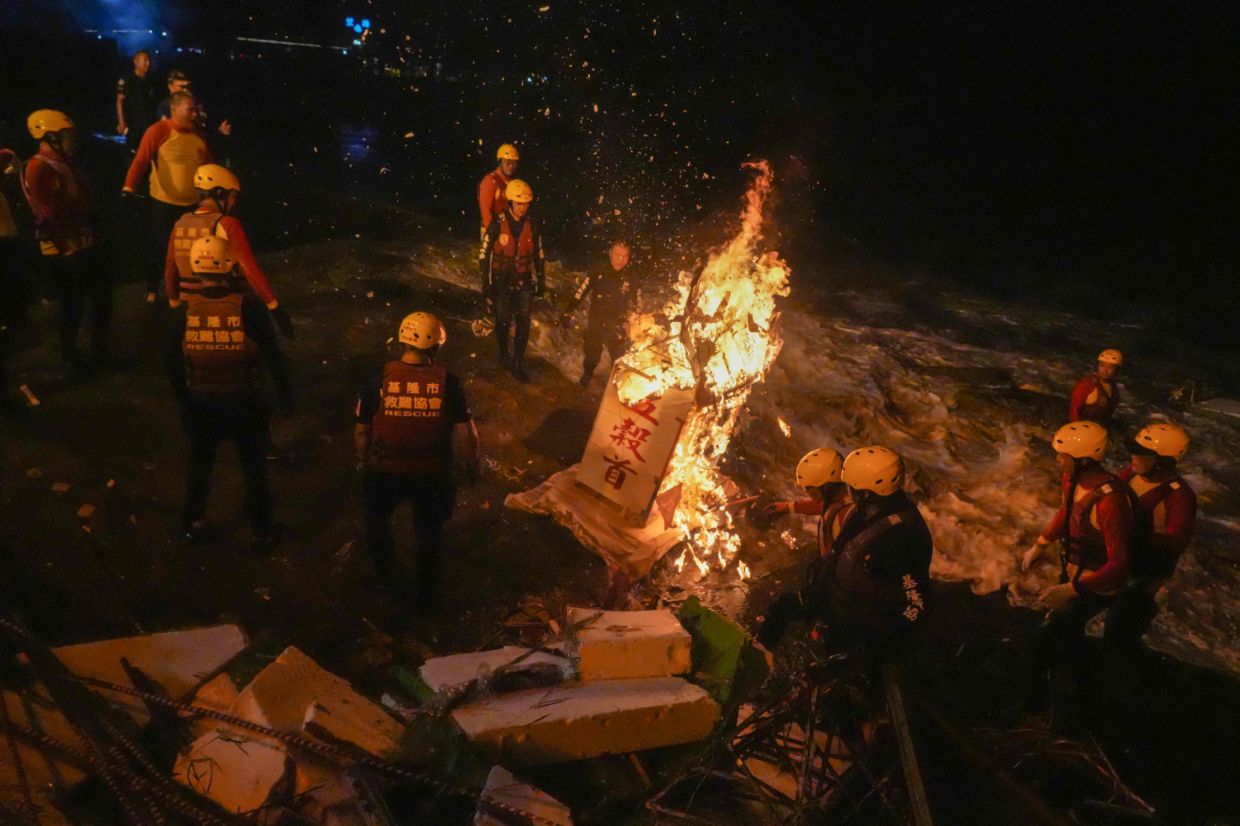 Rescue personnel monitor a burning house-shaped water lantern during the Keelung Mid-Summer Ghost Festival in Keelung on August 26, 2026. The festival is celebrated in the seventh month of the lunar new year calendar among communities in southern China, Malaysia, Singapore, Hong Kong and Taiwan, and marks the belief that the -- Gates of Hell -- are opened to let out the hungry ghosts who then wander in the land of the living while foraging for food. During the festival food offerings are made while paper money and joss sticks are burnt outside homes to keep the spirits of dead ancestors happy and to bring good luck. -- Photo by Zheng Hui-Yu / AFP