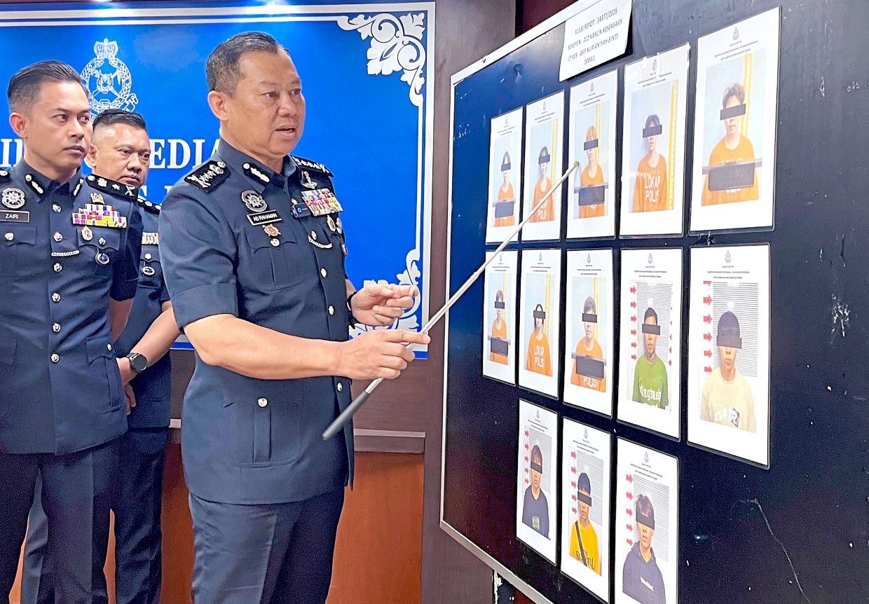 In custody: Comm Ab Rahaman pointing at photos of the 13 suspects arrested in relation to the death of a 17-year-old girl in Kulai. — YEE XIANG YUN/The Star