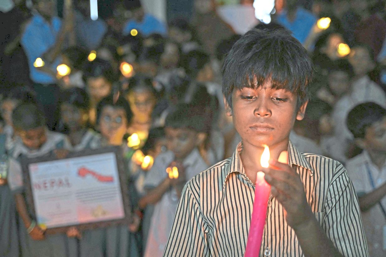 Holding out hope: A school student holding a candle as he pays homage to people who died in Nepal’s flash flood, in Chennai. — AFP