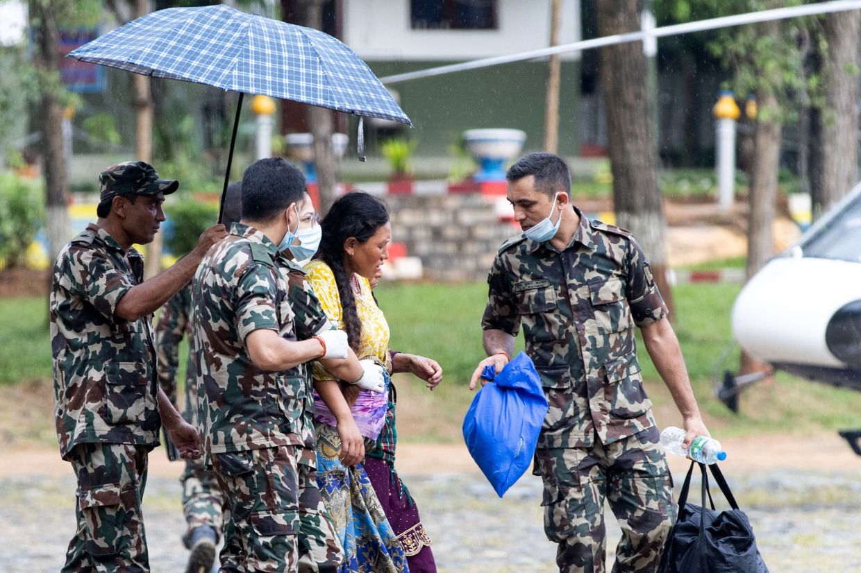Nepali Army personnel evacuating a pregnant woman during rescue operations after flash floods, at Trishuli camp on Aug 28, 2026. - AFP