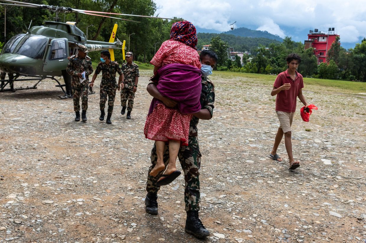 A member of the Nepal Army carrying a woman, after she was rescued and airlifted from flood-affected areas, at Maithali Barrack, an army training centre that serves as a primary base for airlifting survivors. - Reuters