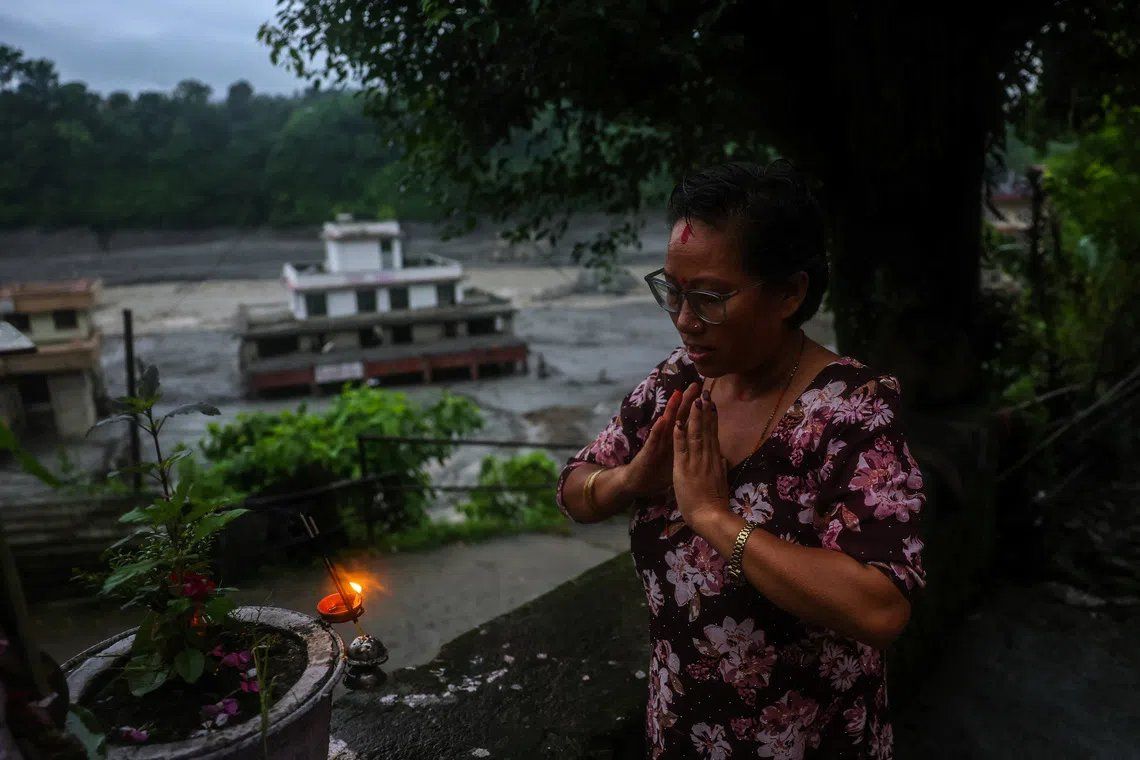 Sarasota Ghale, 42, a resident, prays in front of her house after flash floods and a mudslide, in Trishuli, Nuwakot district, Nepal, Aug 29. -- PHOTO: REUTERS