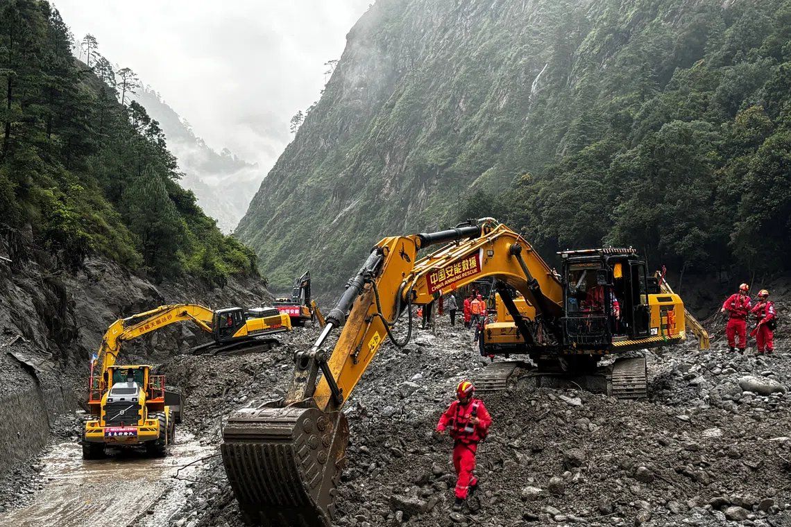 Rescue workers use excavators and loaders to repair a road damaged by a mudslide leading to Gyirong Port in Shigatse, Tibet Autonomous Region, China. -- PHOTO: REUTERS