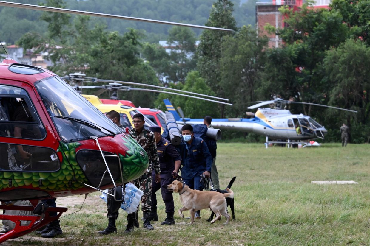 Security personnel with sniffer dogs embark a helicopter enroute to flood-affected Mailung valley, from Trishuli camp in Nepal's Nuwakot district on August 29, 2026. Devastating floods near the border with China this week have killed at least 675 people in Nepal, the Himalayan nation's disaster authority said on August 29. -- Photo by Arun SANKAR / AFP