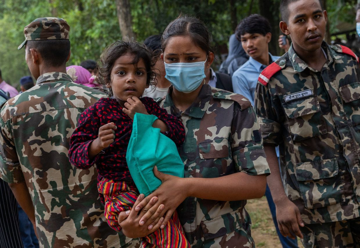 A member of the Nepal Army carries a girl from a helicopter after she is rescued and airlifted from flood-affected areas at Maithili Barrack, an army training centre that serves as a primary base for airlifting survivors, following flash floods and a mudslide, in Trishuli, Nuwakot district, Nepal, on Saturday, August 29, 2026. -- Photo: REUTERS/Adnan Abidi