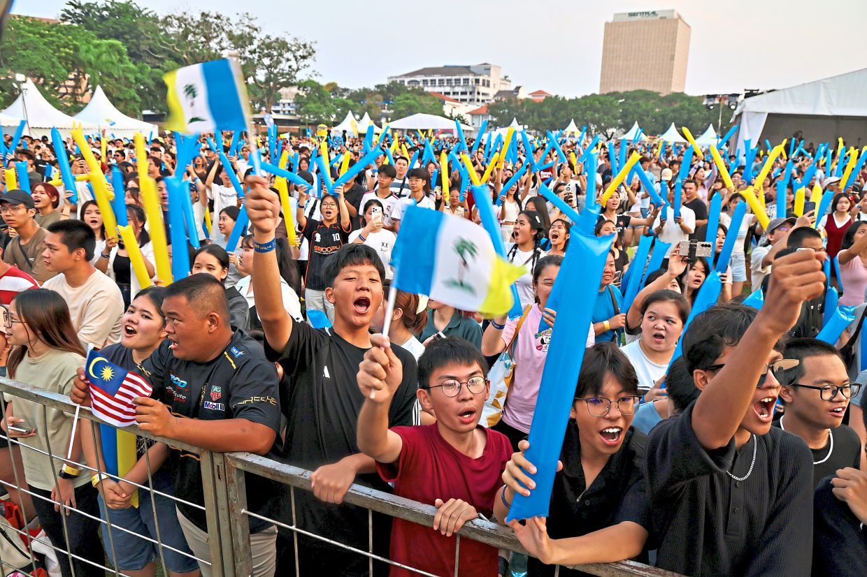 Visitors cheering and waving flags at the festival featuring live performances.