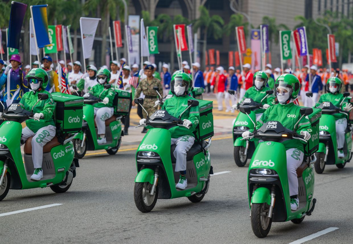 Grab’s EV delivery bikes operated by women partners making their way through the Putrajaya National Day parade.