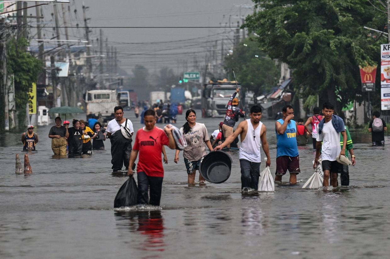 People wade through a flooded street after heavy rains brought by the southwest monsoon in Pampanga on August 31, 2026. -- Photo by Jam STA ROSA / AFP