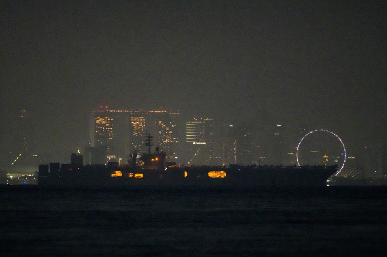 The US Navy aircraft carrier USS Abraham Lincoln sails past Singapore as seen from Batam, Indonesia. -- AP Photo/Dita Alangkara