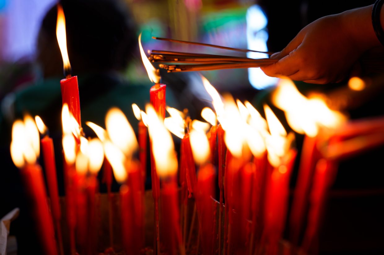 Devotees light incense sticks as they pray before a paper statue of Da Shi Ye, the Guardian God of Ghosts, during the Hungry Ghost Festival in Bukit Mertajam. Photo: AP