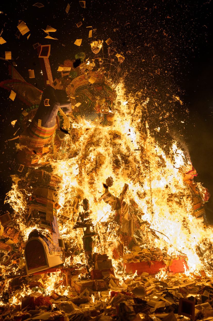 Paper offerings fly through the air as devotees throw them into a fire during the Hungry Ghost Festival in Bukit Mertajam, Penang on Aug 29. Photo: AP