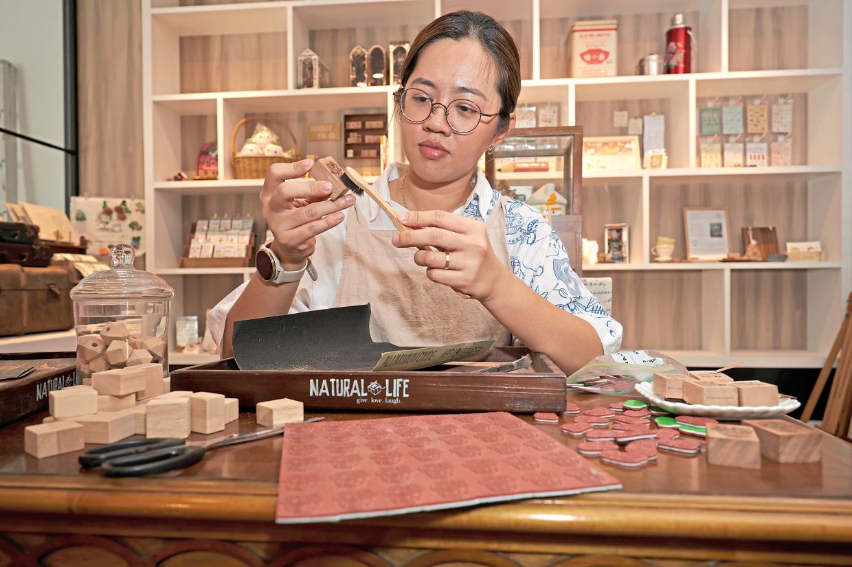 (Left) Elsie brushing dust from a wooden block while crafting her custom-designed rubber stamps.