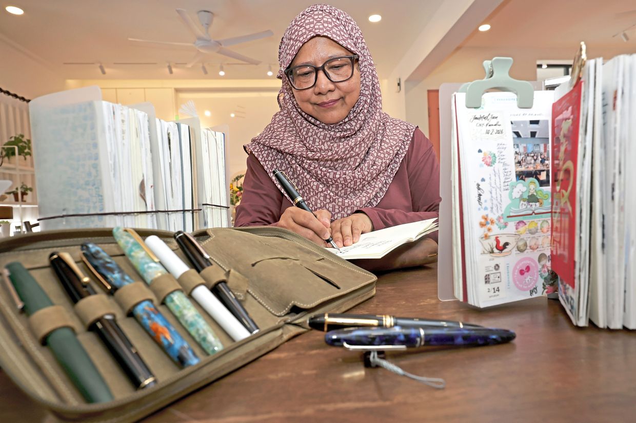 Nurashikin penning down her thoughts while showcasing her elegant fountain pens.
