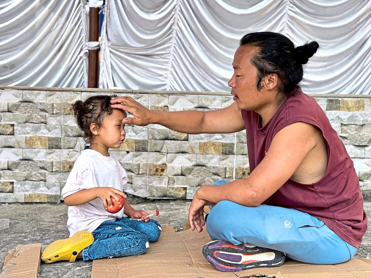 Uncertain future: Lama sitting with his daughter at the monastery. She does not know yet that her mother died in the floods. — AP