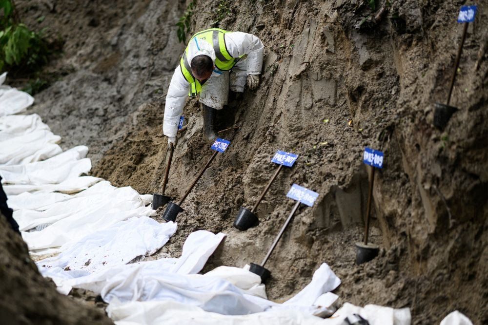 A security personnel puts number-tagged pots next to unidentified bodies of flood victims kept for mass burial at the Gokarna forest reserve in Kathmandu on September 1, 2026. - Photo: AFP