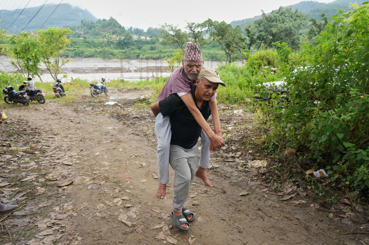 Balaram Gajurel, 86, is carried by his son on his back after getting transported on a zip line constructed to transport stranded citizens across the Trishuli river following flash floods, in Nepal's Nuwakot district, Thursday, Sept 3, 2026. - Photo: AP