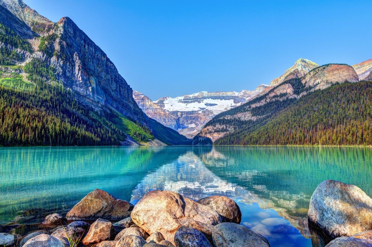 Marvel at the breathtaking beauty of the Canadian Rockies in spring, where turquoise waters meet majestic mountain peaks.