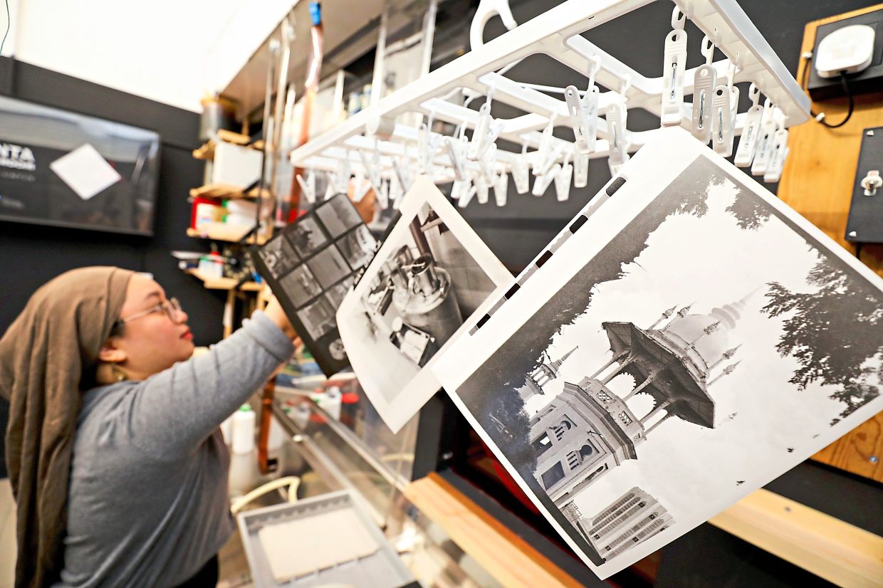 A Kanta Darkroom facilitator assists participants with the printing process. Photo: The Star/Leong Wai Yee