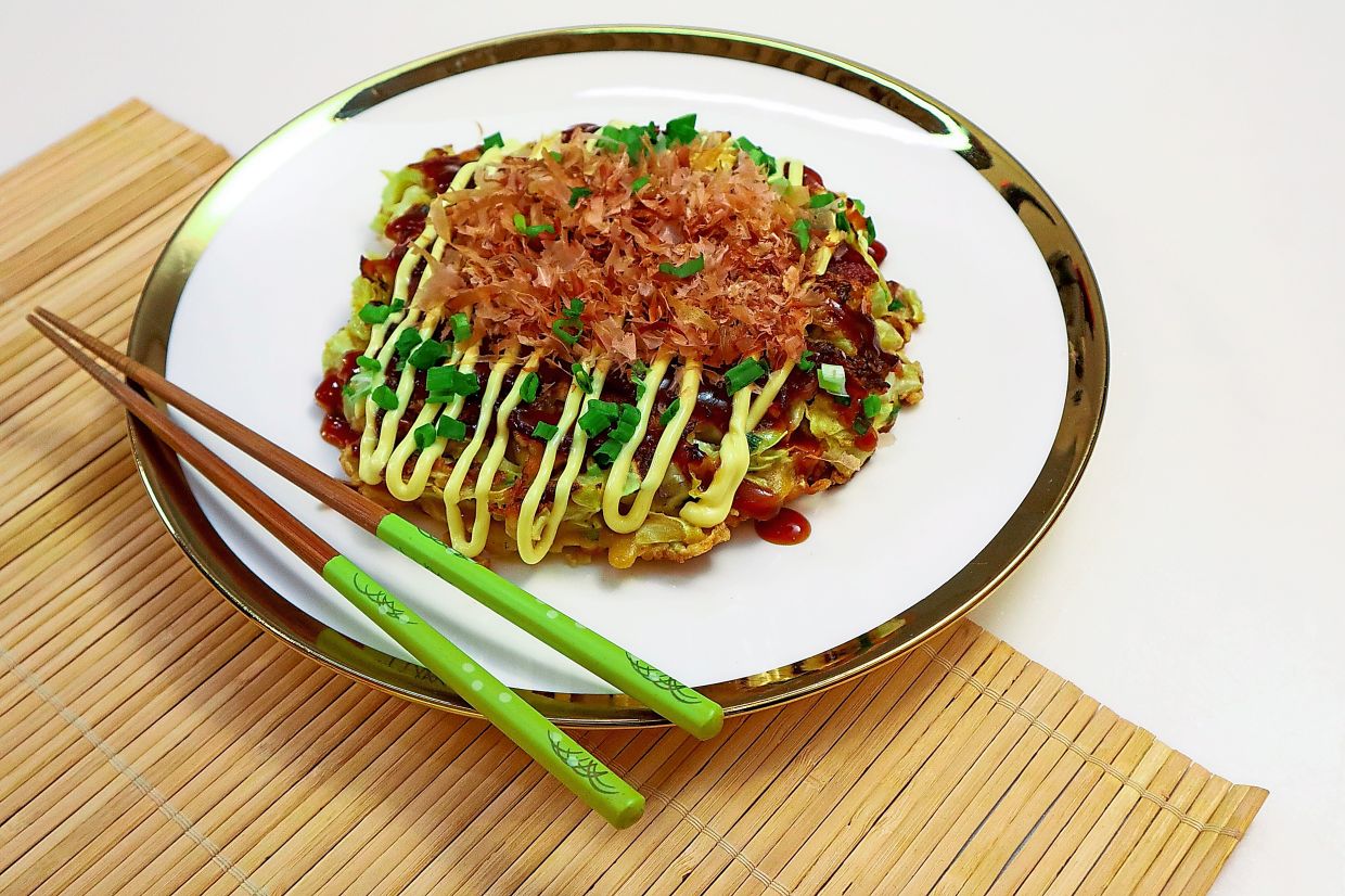 Finish the ‘okonomiyaki’ with a scattering of bonito flakes, then sprinkle spring onions for a pop of colour.