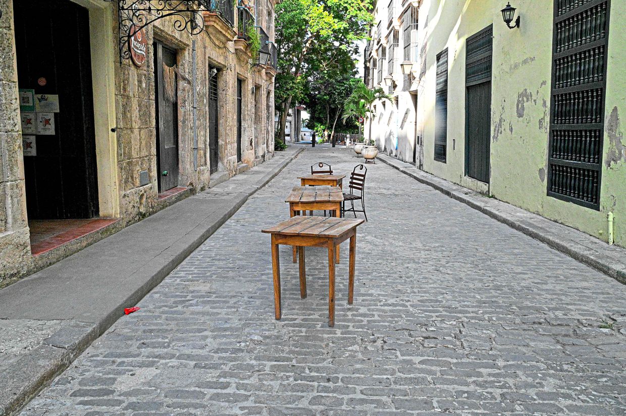 Tables and chairs from closed restaurants are seen on a deserted street in Havana.