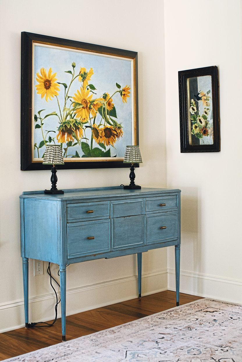 A cabinet and paintings at a corner in the home.