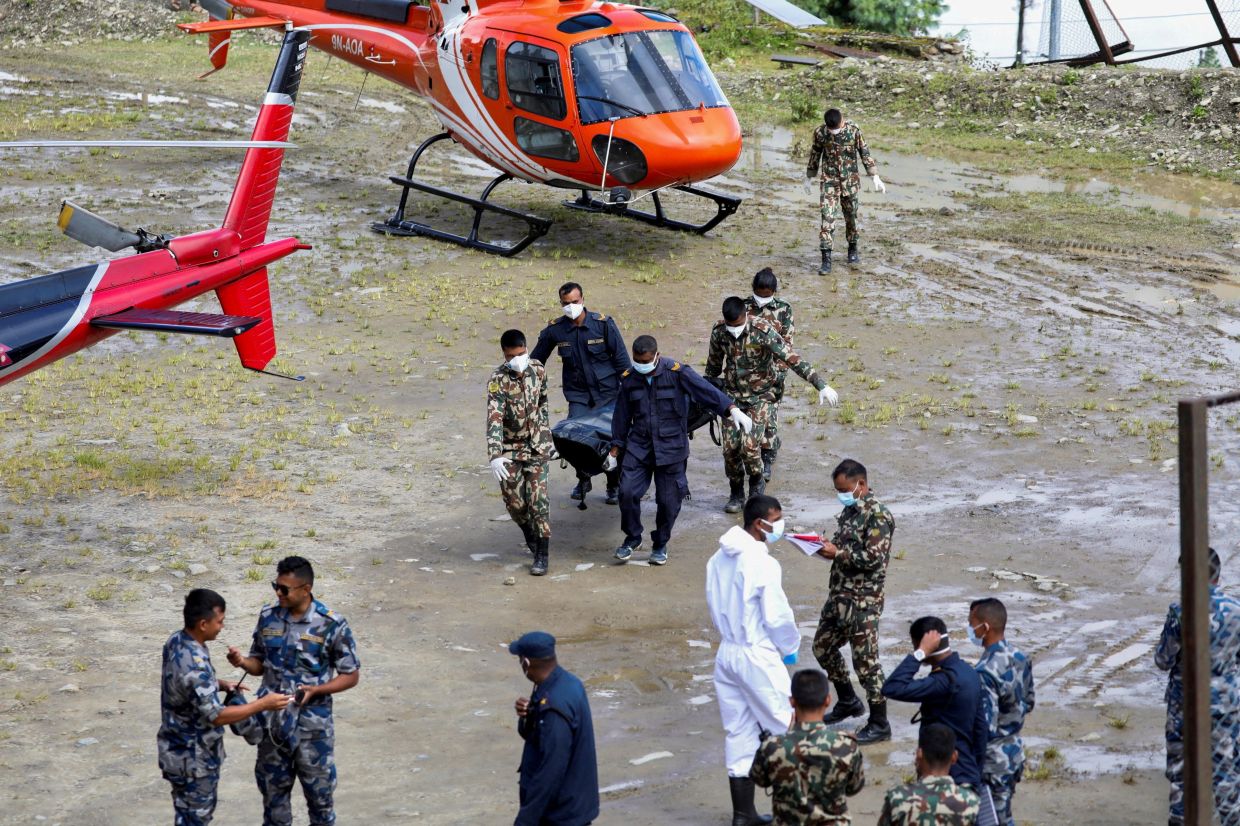Nepal Army and police personnel carry a dead body to be transferred by helicopter from Dhunche, in Rasuwa district, Nepal. -- Photo: Reuters