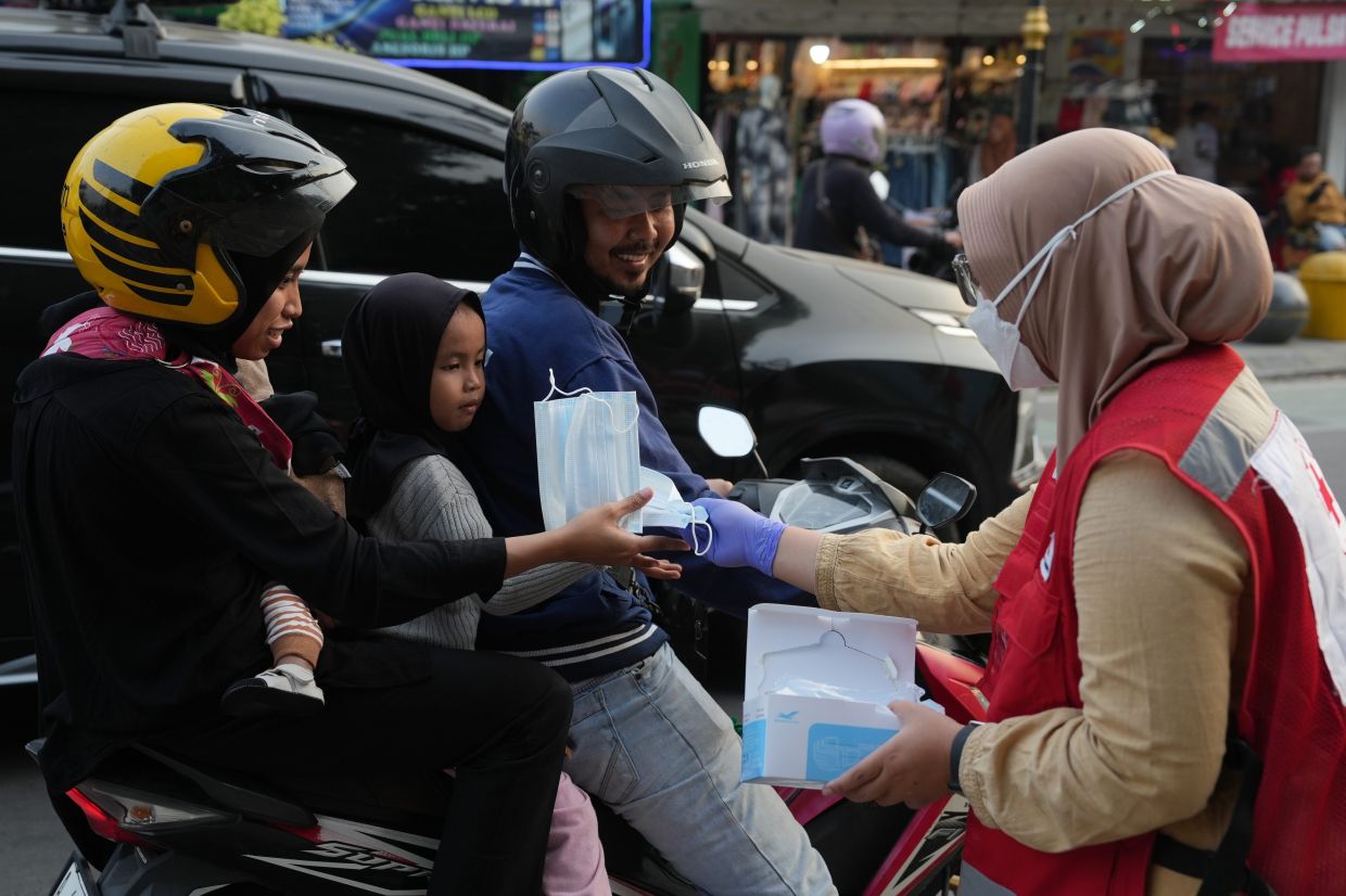 A member of the Indonesian Red Cross hands out face masks to motorists following the ash fall from the eruption of Mount Anak Krakatau, in Serang, Indonesia, on Sunday, Sept. 6, 2026. -- Photo: AP Photo/Dziki Oktomauliyadi