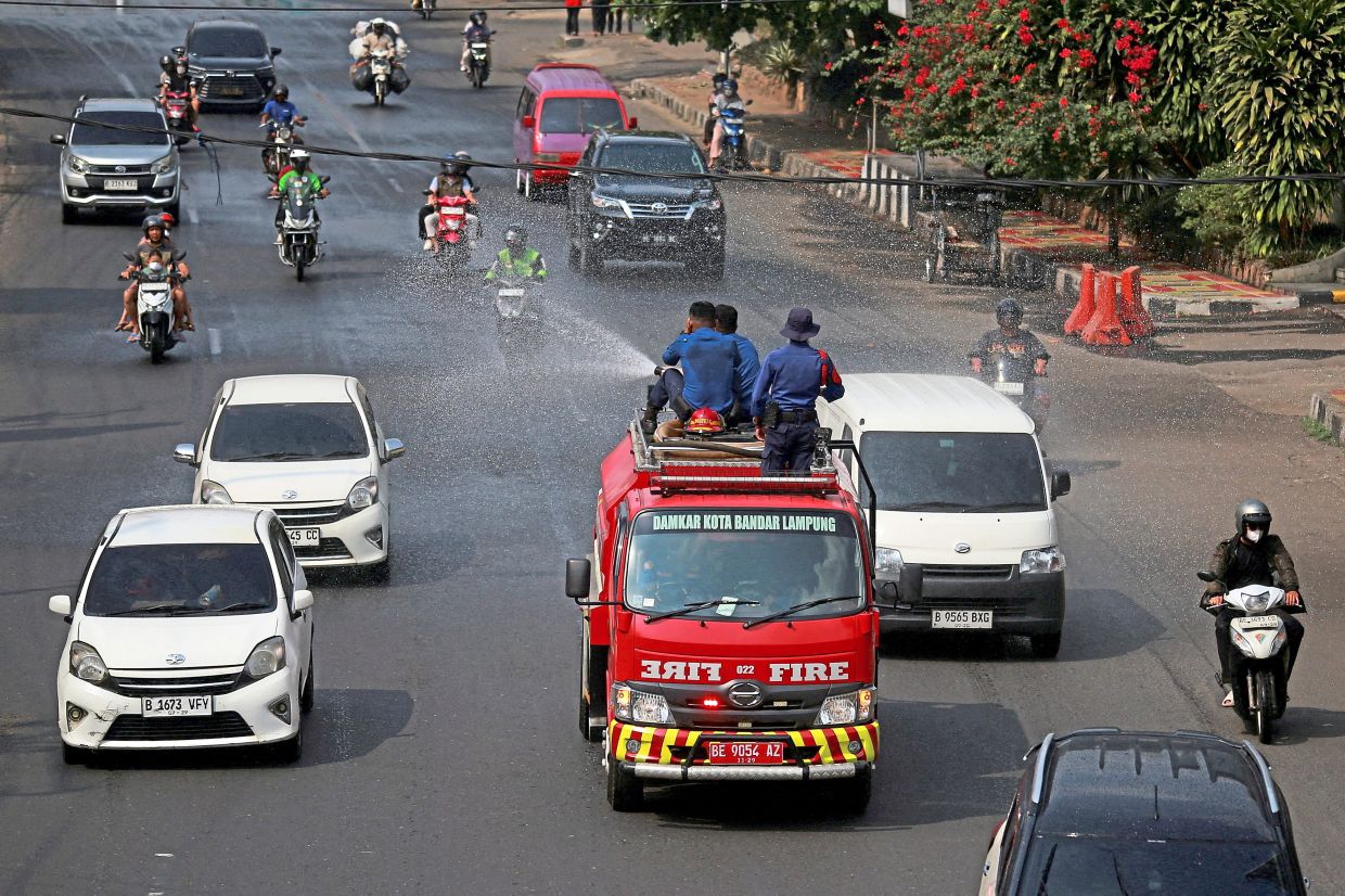 Firefighters spraying water to clear volcanic ash. — Center for Volcanology and Geological Hazard Mitigation/Reuters/AFP 