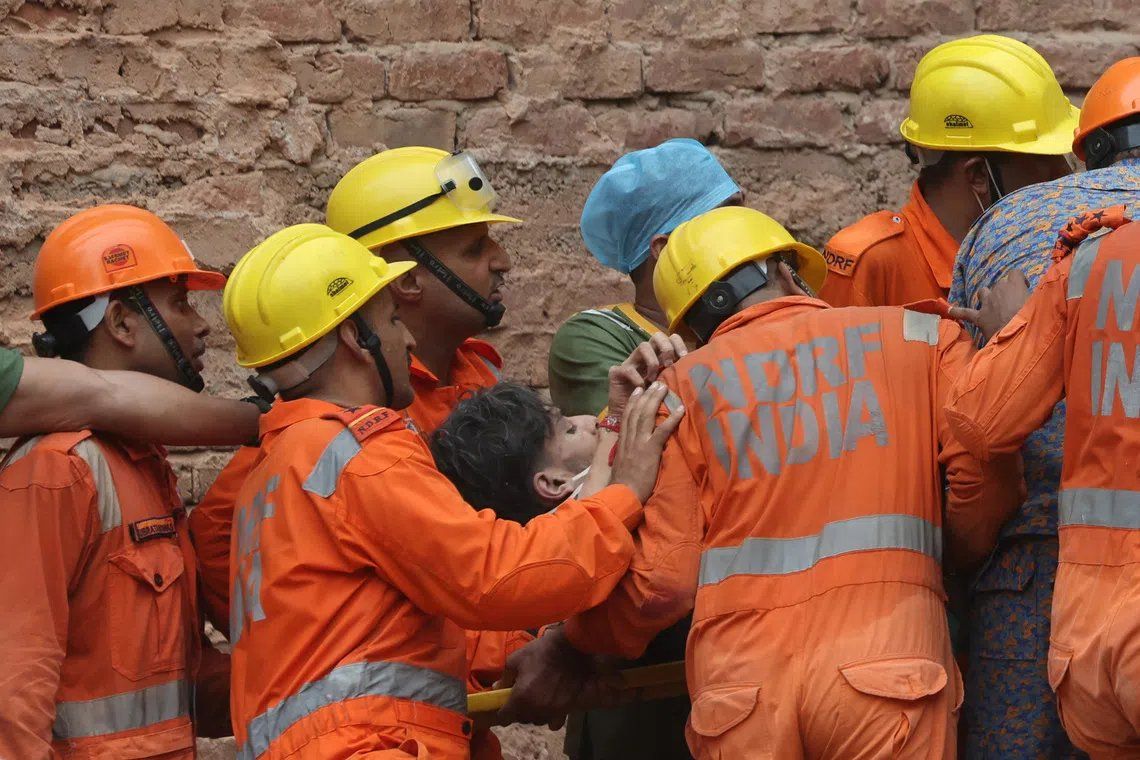 Members of a rescue team carrying a victim out from the rubble after a building collapsed in New Delhi. - Photo: Reuters