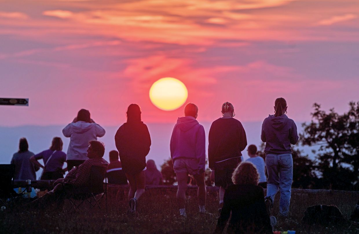 People gather on top of the Feldberg mountain to watch the sunset near Frankfurt, Germany. The methods communities have used to track their lives have been shaped by culture, religion, economics and technology, among others.