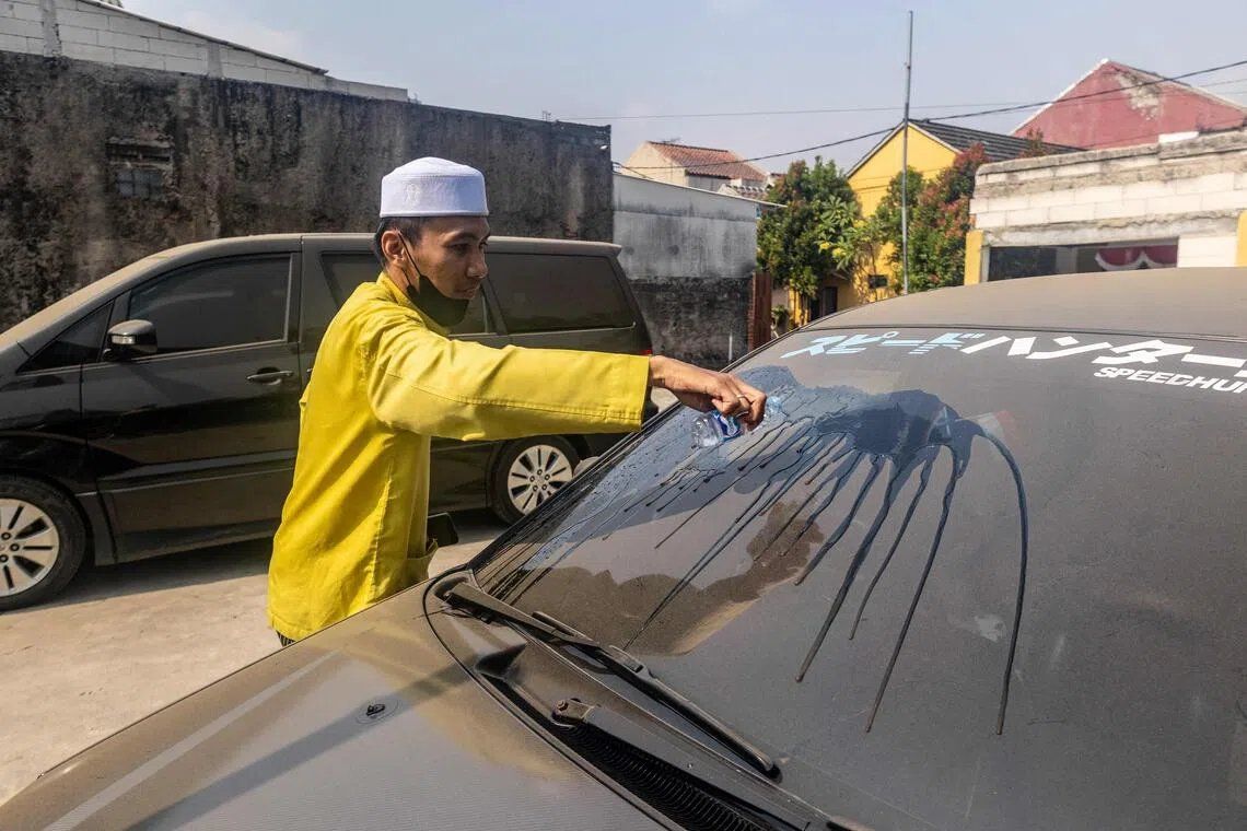 A man clearing volcanic ash from his car windscreen in Bogor, West Java, on Sept 6, following the eruption of Mount Anak Krakatau. - Photo: AFP