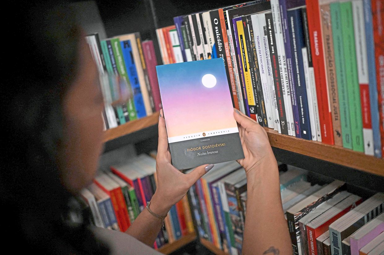 A bookseller holds a copy of the book 'White Nights' at the Leonardo Da Vinci bookstore in downtown Rio de Janeiro, Brazil. Photo: AFP 