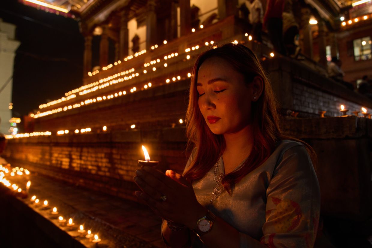 Sumi Lama prays after lighting a candle during a day of mourning for victims of the Aug. 26 floods in Kathmandu, Nepal, on Monday, Sept. 7, 2026. -- AP Photo/Dar Yasin