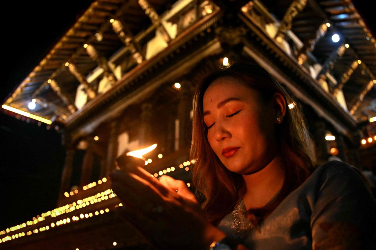 A woman holds an earthen lamp during a gathering at Durbar Square to observe a national day of mourning for victims of flash floods in Kathmandu on Monday, September 7, 2026. Nepal held a national day of mourning on September 7 for victims of devastating glacial floods, as families of missing hydropower workers feared trapped in tunnels prayed rescuers might yet find them alive. -- Photo by Prakash MATHEMA / AFP